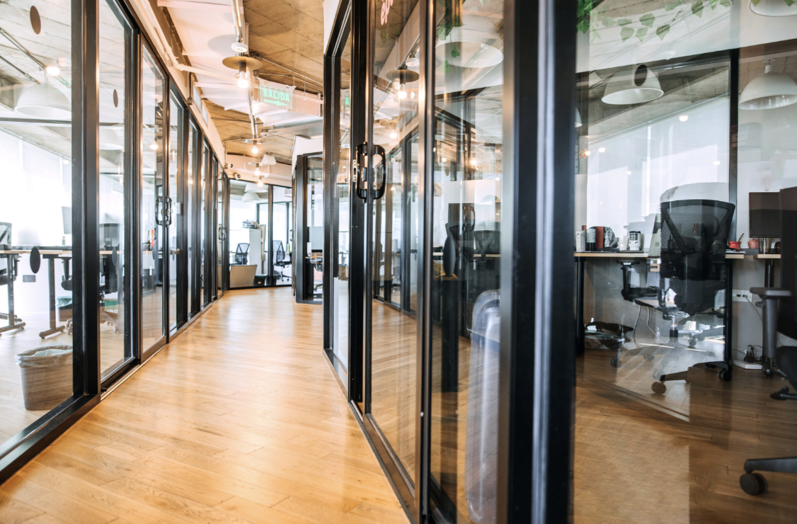 Bright modern office hallway with glass-walled workspaces